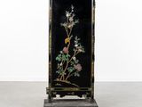 a black and gold painted cabinet with flowers on it