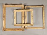 three gold picture frames hanging on a wall next to a mirror