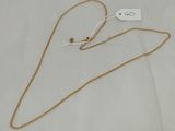 a gold necklace with a tag on it sitting on a white surface