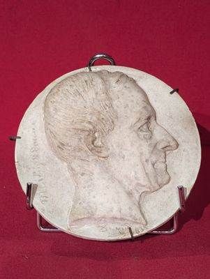 une image représentant le visage d'un homme sur une plaque posée sur un fond rouge