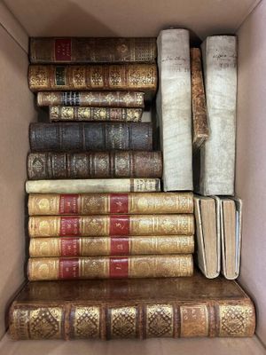 an open cardboard box filled with lots of books sitting on top of each other