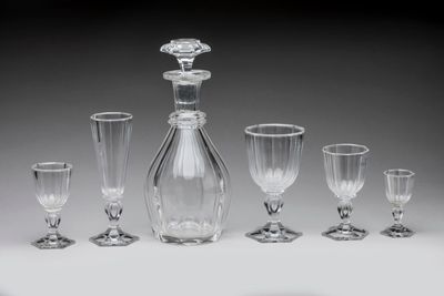 six wine glasses and a decanter on a table