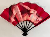 a red fan with a picture of a woman on it