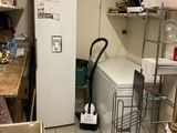 a white refrigerator in a small room with a lot of boxes on the floor