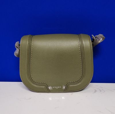 un petit sac à main vert posé sur un comptoir blanc