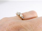 a woman ' s hand holding a pearl and diamond ring