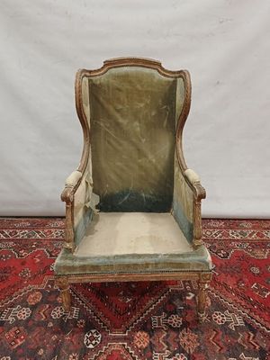 an old chair with a green velvet upholstered seat on a red rug