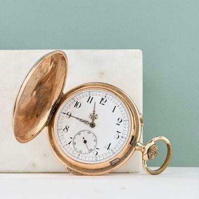 une montre de poche en or posée sur un bloc de marbre