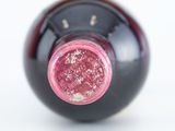 a close up of a wine bottle with a pink cap
