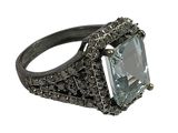 an image of a ring with a large blue stone surrounded by black diamonds