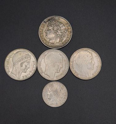 four different types of silver coins on a black surface