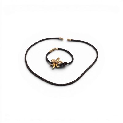 un collier à cordon noir orné d'une breloque en forme d'abeille dorée sur fond blanc