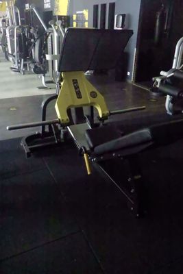 des appareils de musculation jaunes et noirs dans une salle de sport au sol noir