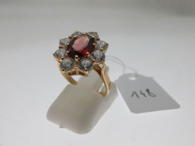 un gros plan d'une bague ornée d'une pierre rouge entourée de pierres blanches