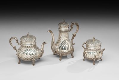 trois théières en argent et une cafetière, posées sur des socles