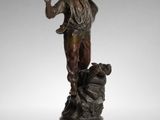 a bronze statue of a woman holding a bird on a pedestal
