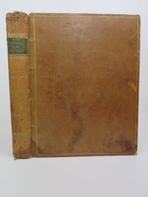un vieux livre à la couverture marron posé sur une table blanche