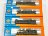 trois boîtes contenant des trains miniatures, posées sur une surface blanche