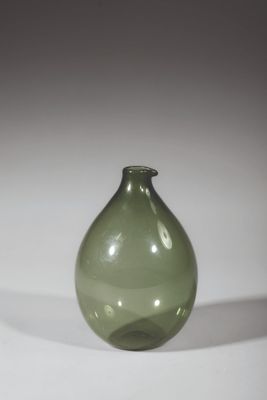 un vase en verre vert posé sur une surface blanche