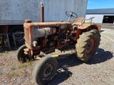 a rusted old tractor parked in front of a building