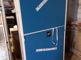 a blue refrigerator sitting in a warehouse with a wooden pallet