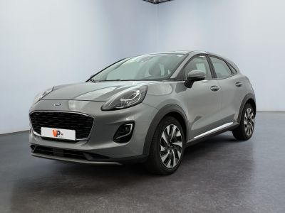Une voiture grise est garée dans une grande pièce au sol noir.