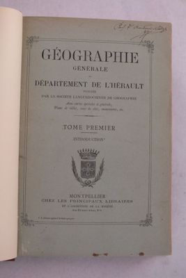 un livre ouvert posé sur une table, sur laquelle figure une image représentant des armoiries