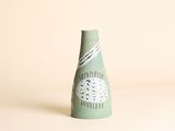 un vase vert orné d'un motif sur un fond blanc
