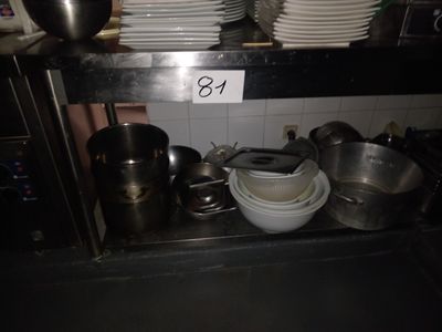 Plusieurs casseroles et poêles sont empilées sur une étagère dans une cuisine