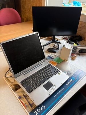 un ordinateur portable posé sur un bureau, à côté d'un écran d'ordinateur