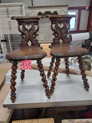 pair of antique carved wood chairs on display in a store