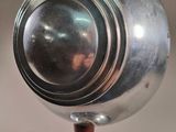 a silver object on a wooden stand with a clock on it