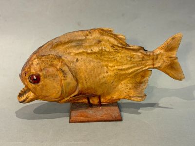 une sculpture en bois représentant un poisson, posée sur un socle en bois