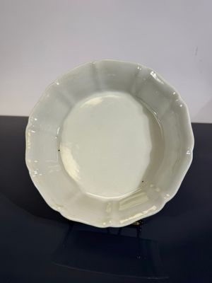 une assiette blanche posée sur une table noire, sur fond blanc