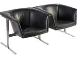 two black leather chairs sitting next to each other on a white surface