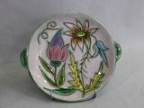 une assiette ornée d'un motif floral, posée à côté d'un vase