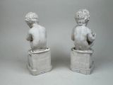pair of white statues of children sitting on books on a white background