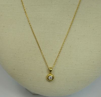 a gold necklace with a diamond on a mannequin head