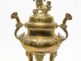 une grande urne en laiton posée sur un socle orné d'un dragon