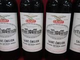 six bottles of red wine are lined up on a table