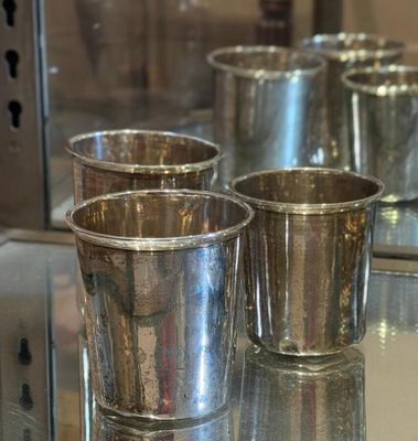 four silver cups sitting on a glass table