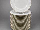 a stack of white and gold dinner plates with gold trim