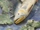 a fish that is sitting on a plate with leaves on it