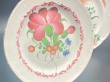 two plates with flowers painted on them sitting on a table
