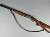 a rifle on a white surface with a wooden handle