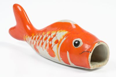 une figurine de poisson orange et blanche posée sur une surface blanche
