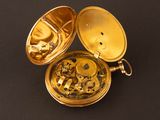 a gold pocket watch sitting on a black surface