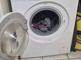 a washing machine sitting on the floor next to a trash can