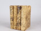 trois vieux livres empilés sur une surface blanche