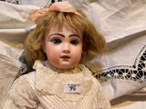 a doll that is sitting on a bed with a name tag on it